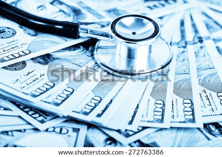 A medical stethoscope on dollars, blue toned 
