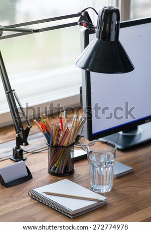 Light and cozy workplace with color pencils and glass of water