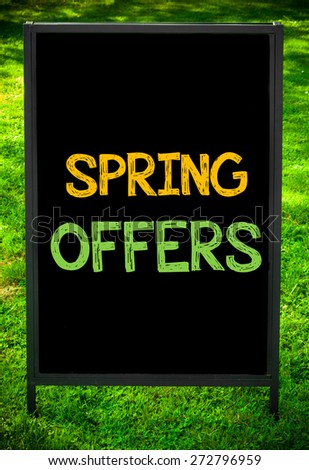 SPRING OFFERS  message on sidewalk blackboard sign against green grass background. Copy Space available. Concept image