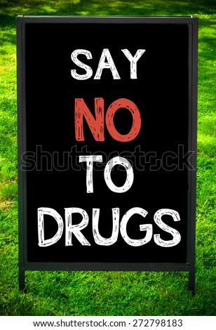 SAY NO TO DRUGS  message on sidewalk blackboard sign against green grass background. Copy Space available. Concept image