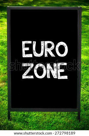 EURO ZONE  message on sidewalk blackboard sign against green grass background. Copy Space available. Concept image