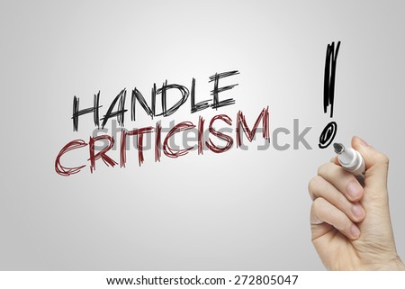 Hand writing handle criticism on grey background