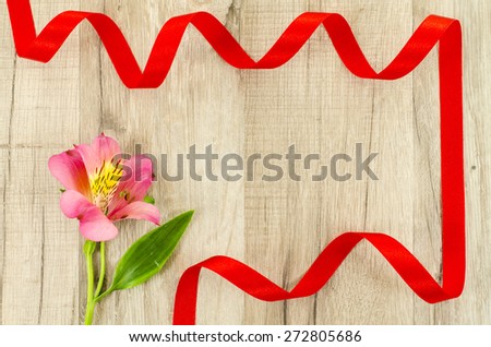 Empty wooden background with colorful flower and red ribbon