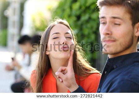 Woman trying to kiss a man and he is rejecting her outdoor in a park Royalty-Free Stock Photo #272821442