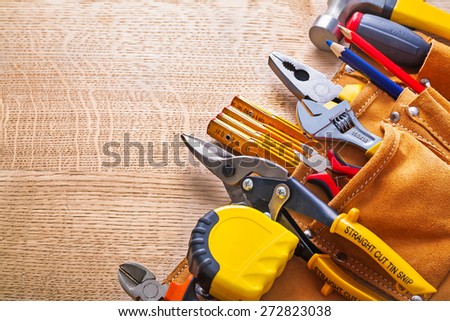 tape measure pliers nippers steel cutter pencil hammer in toolbelt on wooden board Royalty-Free Stock Photo #272823038