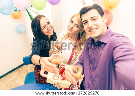 Group of friends celebrating birthday - Young man holding camera and taking a picture with camera while at his girlfriend's party - Attractive people at party toasting champagne glasses and having fun