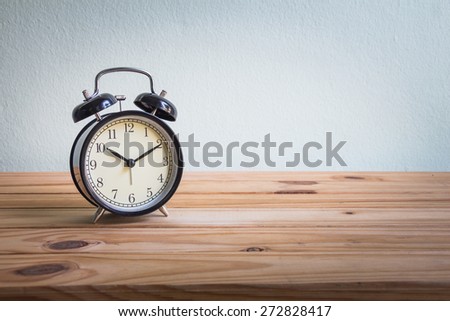 Still life with vintage clock on wooden table over grunge background