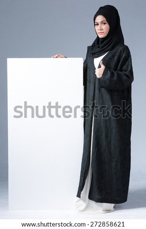 Portrait of muslim woman wearing scarf showing blank board, copy space