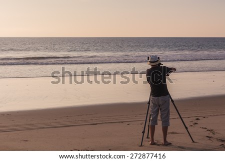 Silhouette Of A Young Photographer Taking Pictures  On The Pacific Ocean Sunset
