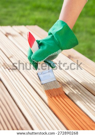 Applying protective varnish on a patio wooden floor, diy maintenance concept