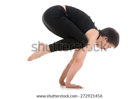 Sporty young man working out, doing handstand yoga asana, Crane (Crow) Pose, Bakasana for shoulders, upper back, arms and wrists Royalty-Free Stock Photo #272921456