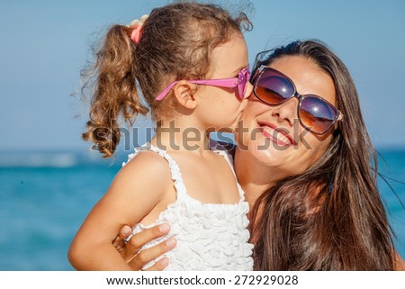 Mother and daughter playing on the beach at the day time. Concept of friendly family.