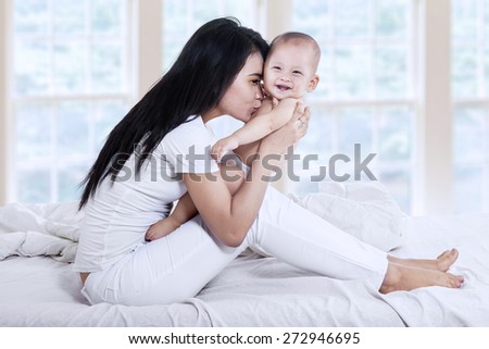 Attractive mother kissed her baby on the bedroom