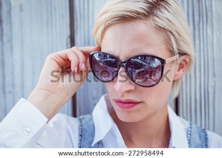 Pretty blonde woman wearing sun glasses on wooden background