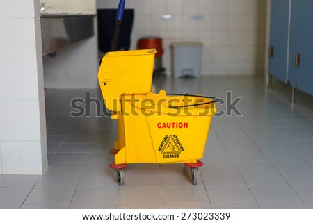 Mop bucket on wet floor in toilet.