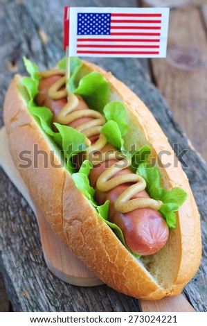 hotdog sandwich with yellow mustard sauce and lettuce on a wooden background
