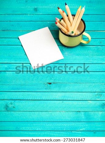 Still life, business, education concept. Pencils in a mug with notepad on a wooden table. Selective focus, copy space background, top view