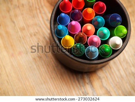 Still life, business, education concept. Crayons in a mug on a wooden table. Selective focus, top view