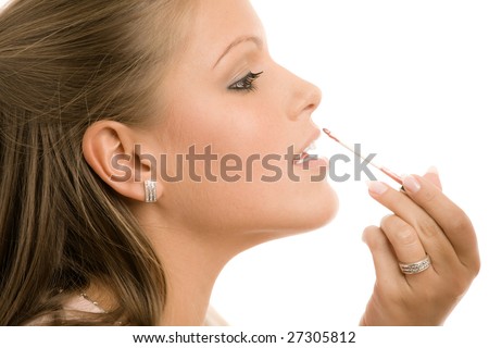 Beautiful young woman applying makeup, putting on lip liner. Isolated on white background.