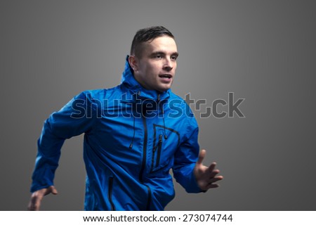 Young sportsman jogging. Studio shot on gray background.