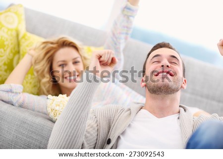 A picture of sport fans cheering at home while watching tv
