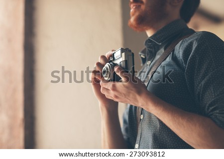 Hipster man searching for an interesting subject for his photo shooting and holding a vintage camera