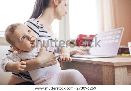 Young mother in home office with computer and her daugher Royalty-Free Stock Photo #273096269