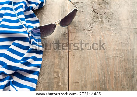 Summer sea-striped cloth and sunglasses on wooden background