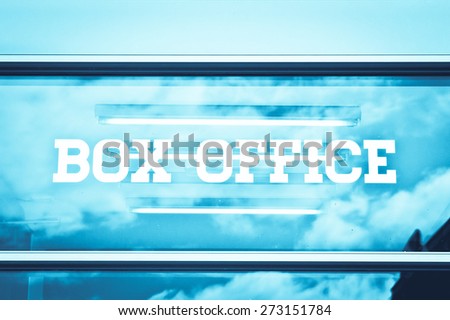 Sign for a box office on a glass panel with reflections of the sky