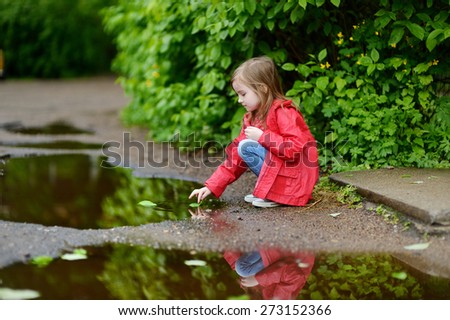 Adorable girl playing in a puddle on rainy summer day