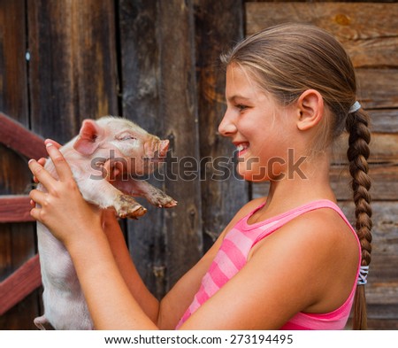 Young farmer - Happy girl holding a white piglet in her hands.