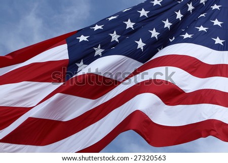 Picture of a huge American Flag waving in the breeze on a sunny day.