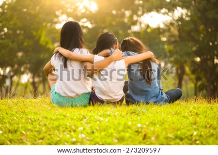 Back view of cute girls seated on green grass and relaxing Royalty-Free Stock Photo #273209597