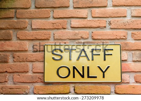 Yellow Staff only warning sign on retro style brick wall 