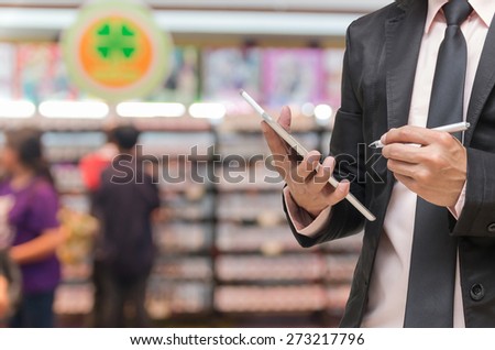 Businessman using the tablet on on Abstract blurred photo of book store with people background