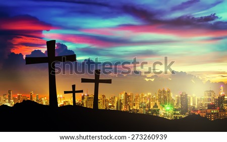 cross silhouette on mountain with twilight sky and cityscape on background.