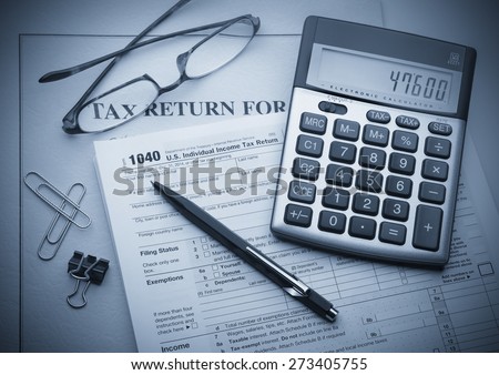 Calculating numbers for income tax return with pen, glasses and calculator Royalty-Free Stock Photo #273405755