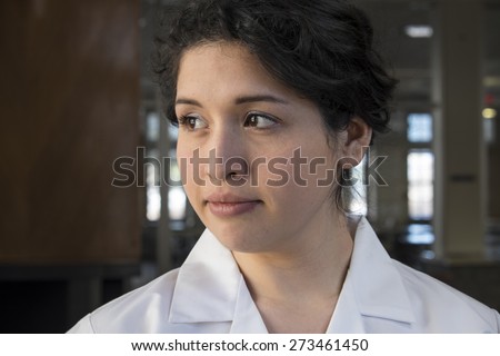 Hispanic female health professional in labcoat, looking off camera