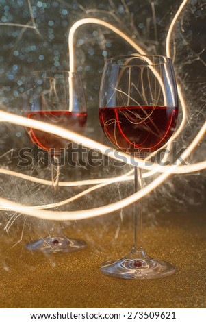 Two rose wine glasses on gold glitter surface lit by sparkling sticks