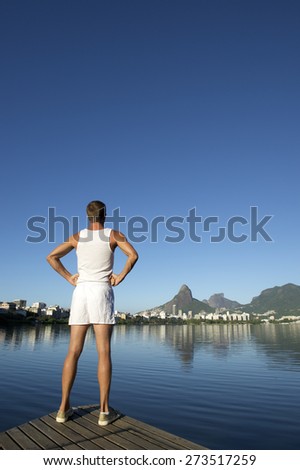 Athlete in white sport uniform standing with hands on hips in front of Rio de Janeiro Brazil skyline at Lagoa lagoon