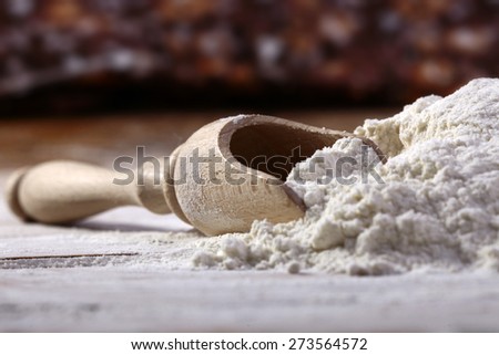 Wooden measure spoon and bunch of flour closeup, horizontal picture