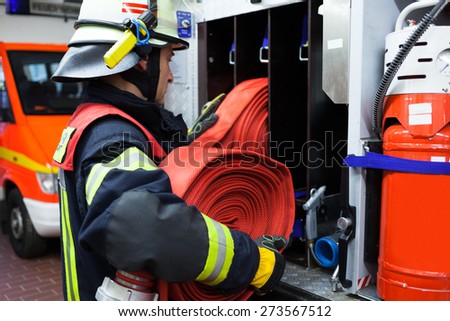 Firefighter in the fire station with hose Royalty-Free Stock Photo #273567512