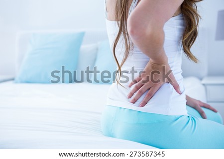 Attractive woman with back pain at home in the bedroom Royalty-Free Stock Photo #273587345