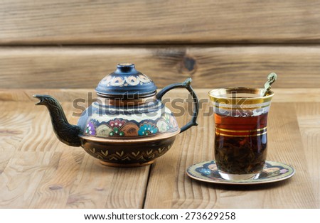 Traditional Turkish tea set: vintage glass cup with teapot on wooden table