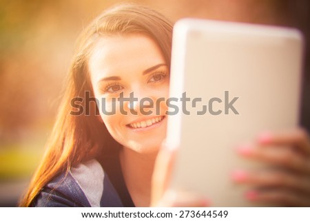 Beautiful girl using tablet or ebook outdoor