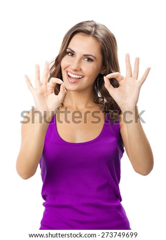 Happy smiling young woman in casual smart lilac clothing, showing okay gesture, isolated against white background