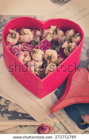 vintage concept   heart with dry flowers  on pile of old photos and key, retro toned