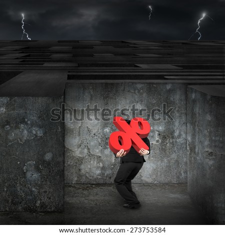 Man carrying big 3D red percentage sign entering the huge maze with dark night cloudy sky background