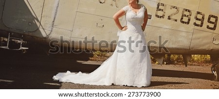 Wedding picture of happy bride next to old airplane. 