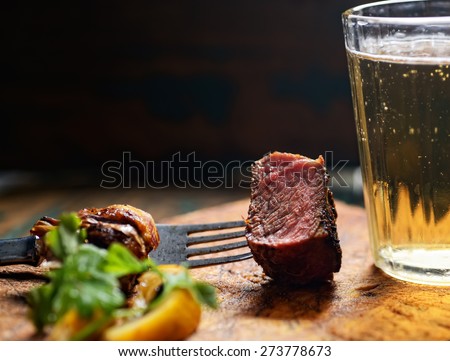 piece of steak on a fork with a beer Royalty-Free Stock Photo #273778673